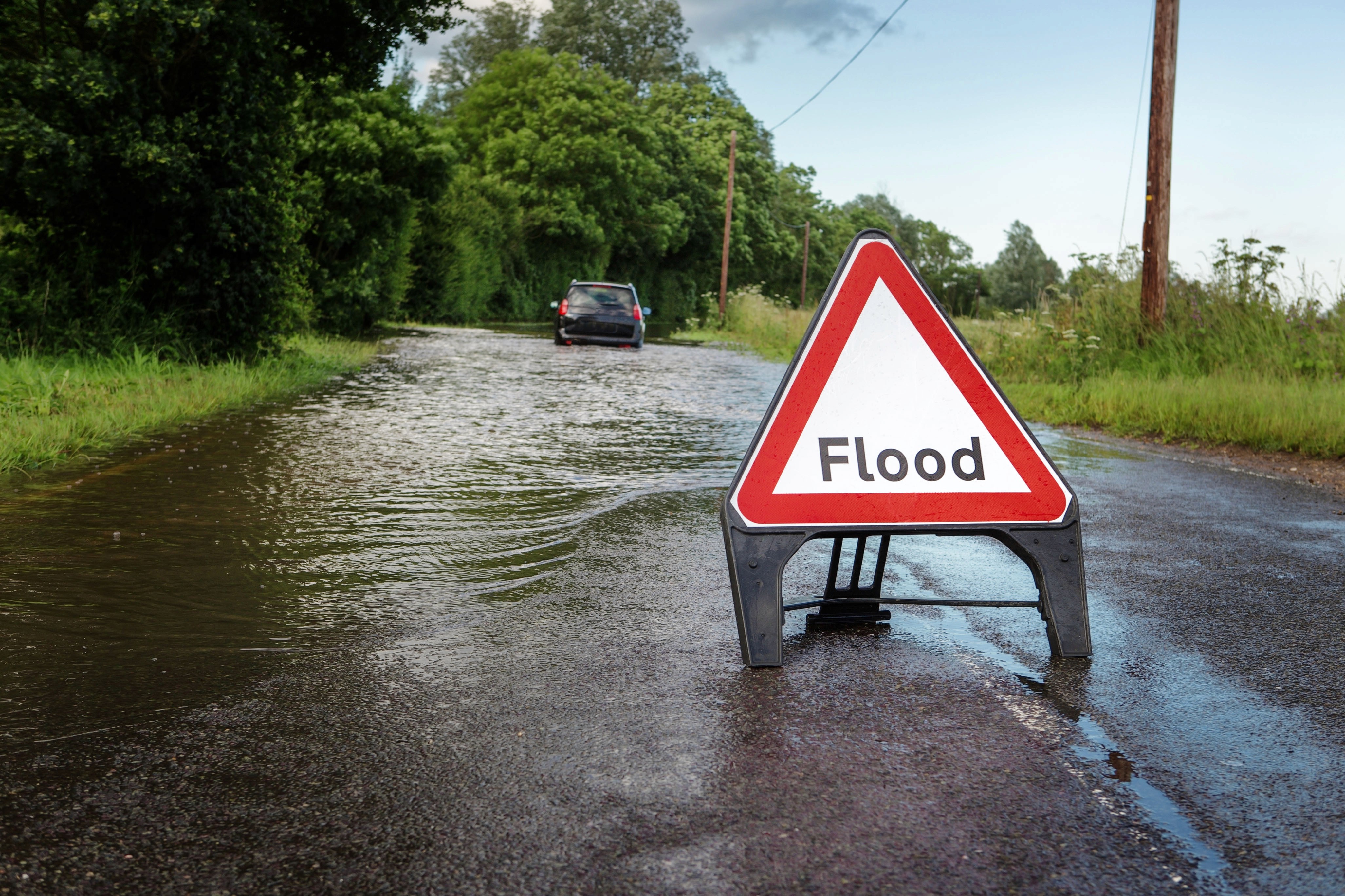 An image of a flood in a road with a warning sign